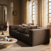Modern brown sofa with textured fabric and matching decorative pillows, set against a warm, light-filled room.
