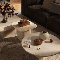 Stylish cream coffee tables with soft curves, complemented by earthy decor and a neutral-toned rug.