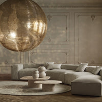 Luxurious beige and cream curved sofa with a textured golden pendant chandelier, set against a warm neutral backdrop.