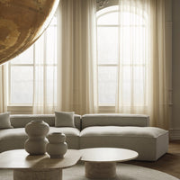 Light beige sofa with soft gray cushions, wooden coffee table, and neutral decor in a bright, airy room.