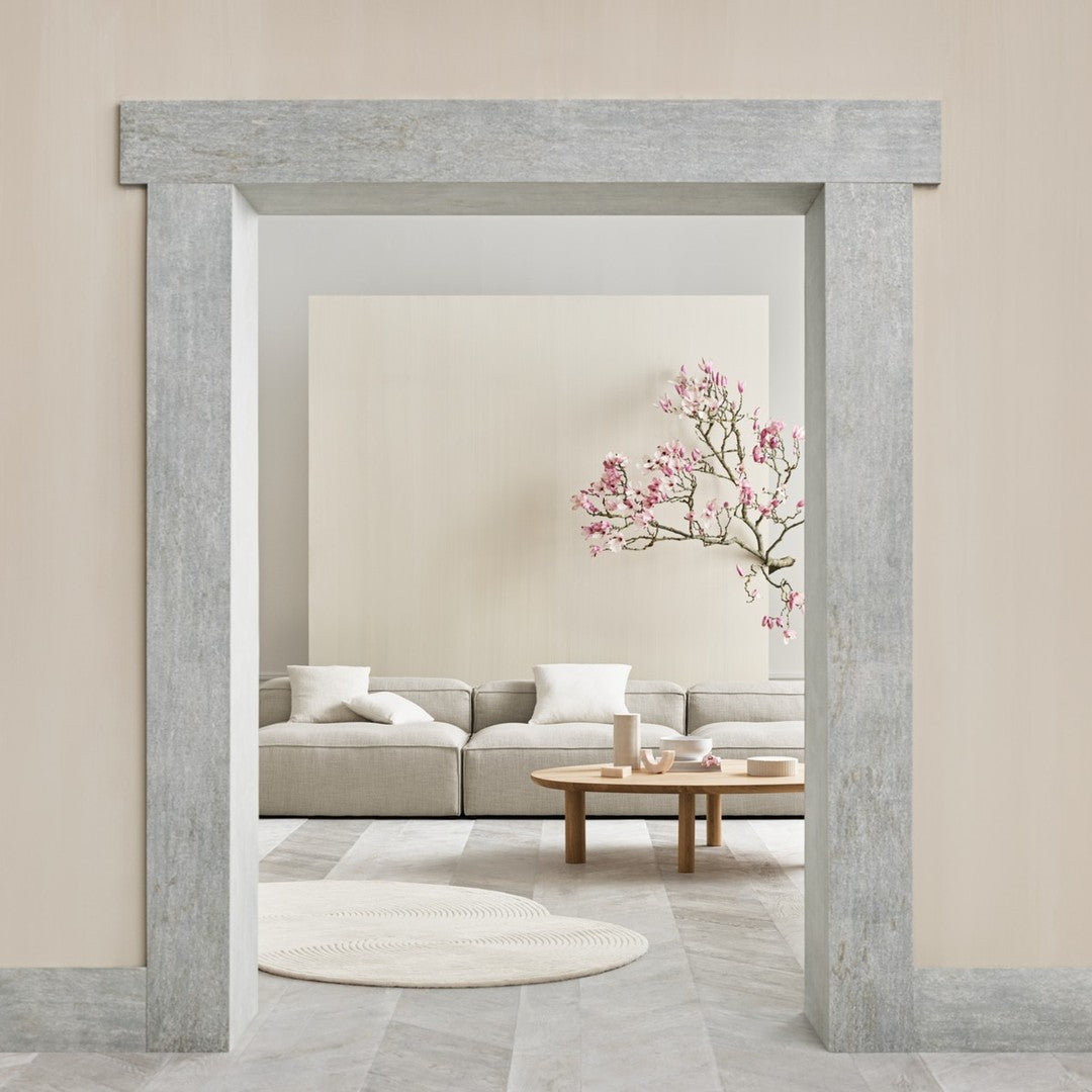 "Soft gray textured wall frame with pastel pink floral decor and neutral beige living room furnishings."