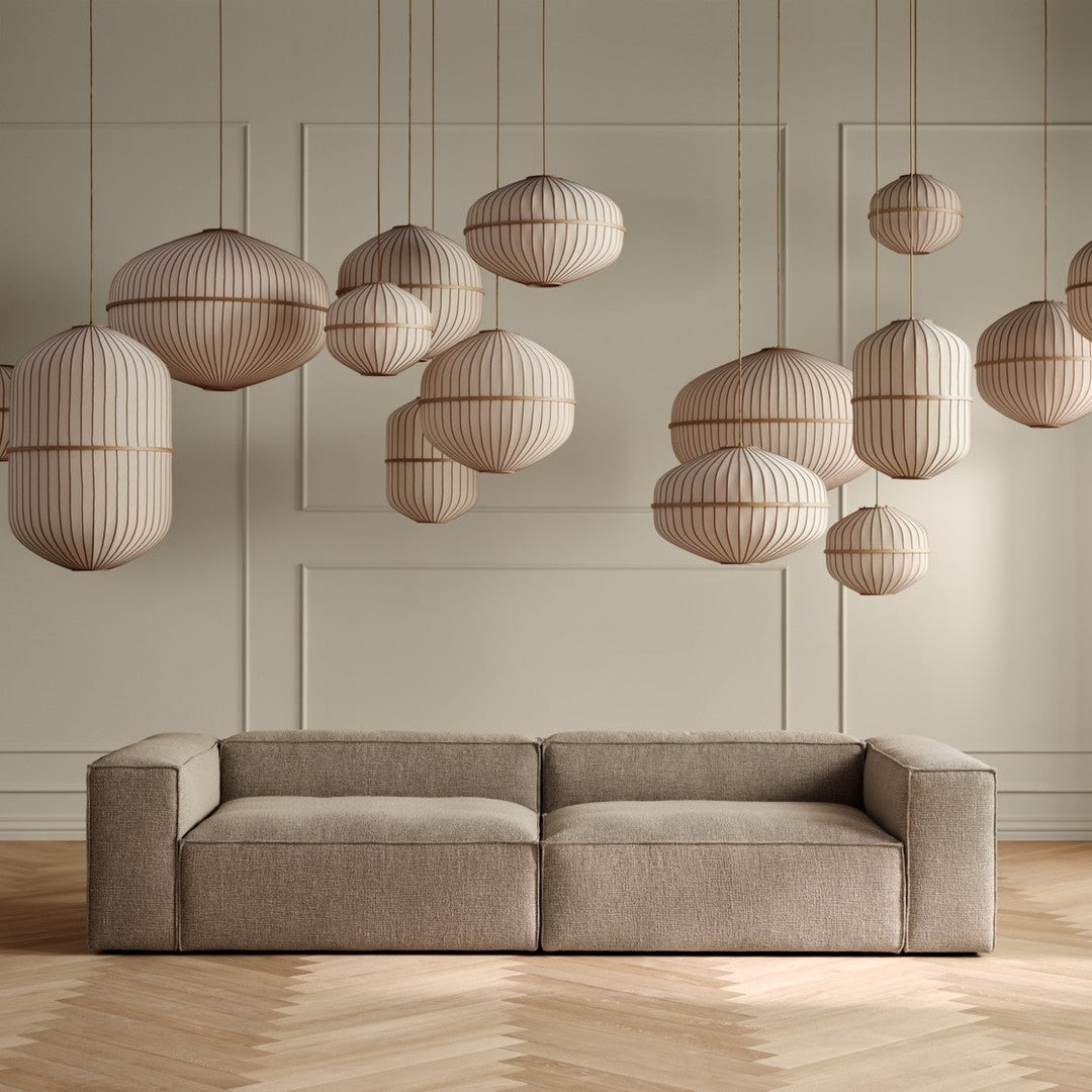 "Beige sofa with textured fabric and striped hanging pendant lights in soft tan tones, set against a light-colored wall."