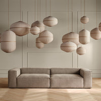 "Beige sofa with textured fabric and striped hanging pendant lights in soft tan tones, set against a light-colored wall."
