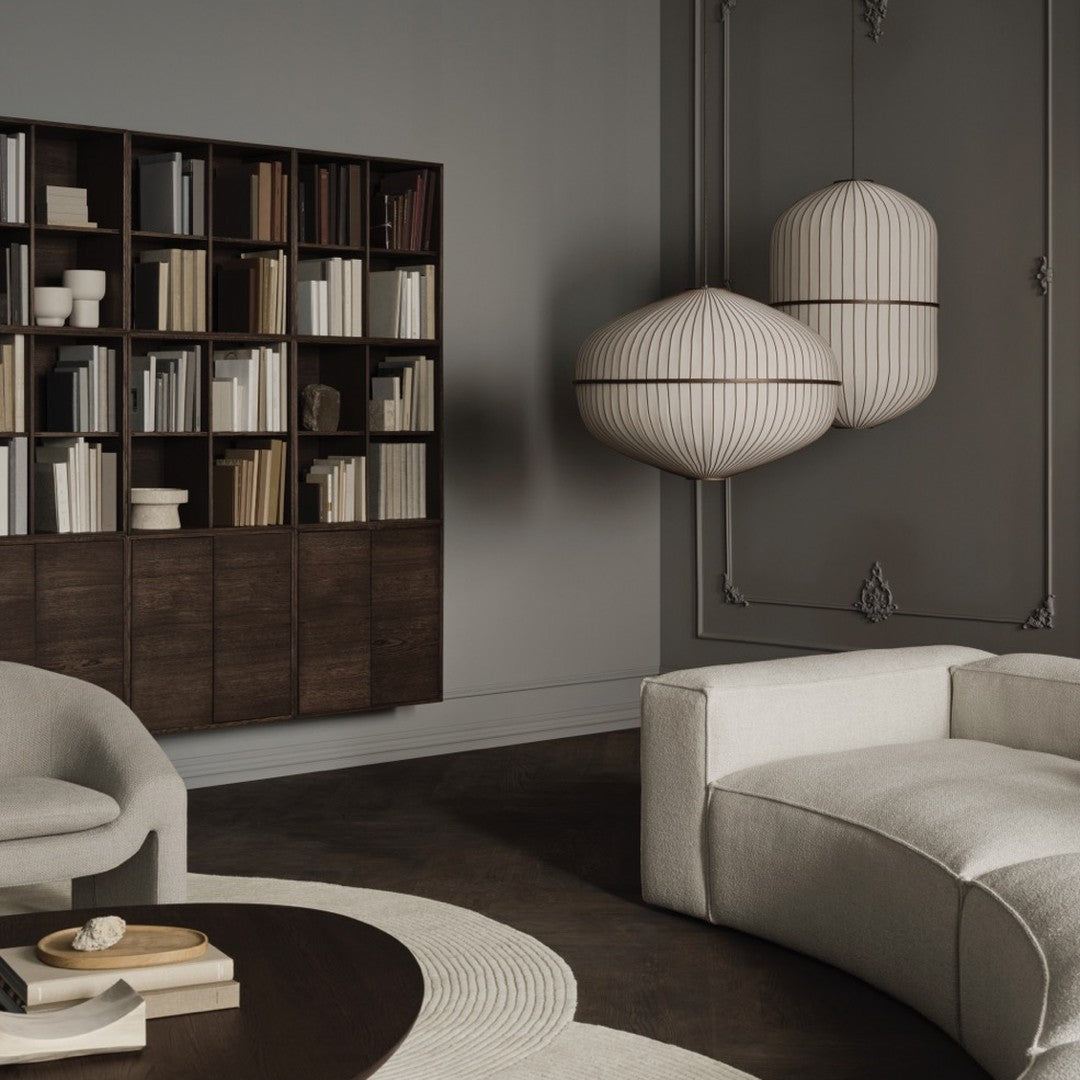 Elegant dark wood bookshelf with white shelves, paired with round cream fabric chairs and textured beige decor.