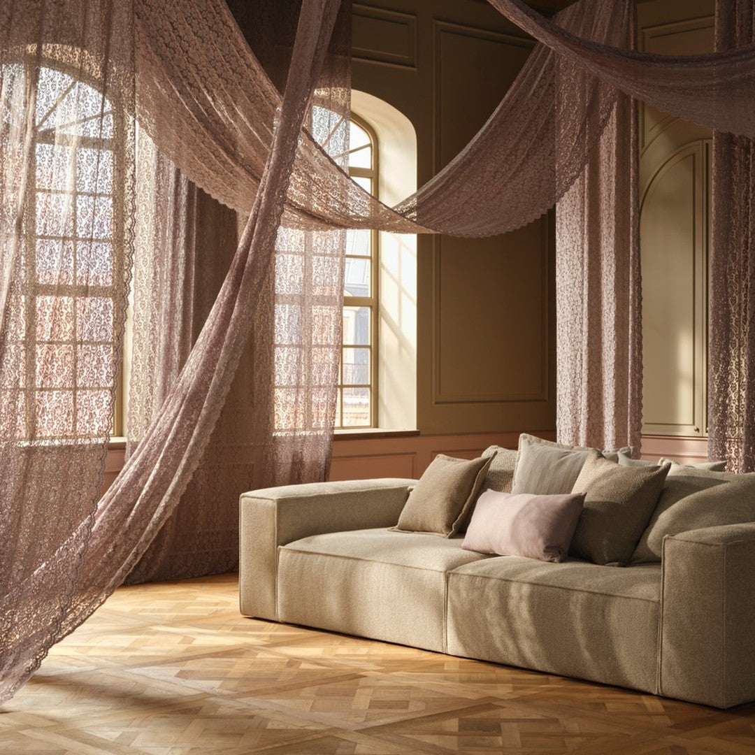 Beige sofa with soft, muted pillows; sheer, draping curtains in soft pink create a warm, cozy atmosphere.