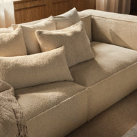 Light beige sofa with textured fabric and assorted cushions in soft, neutral tones, perfect for modern interiors.
