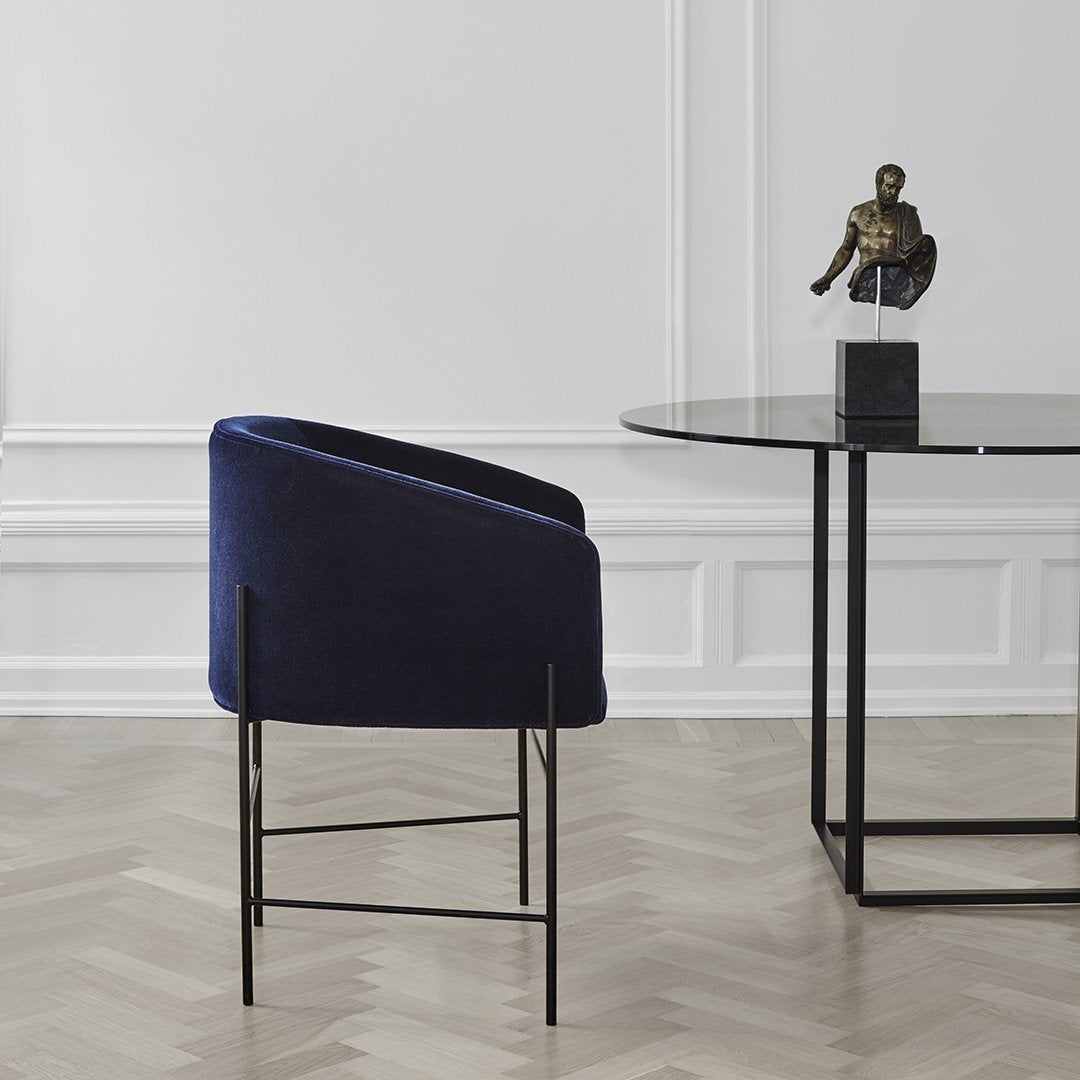 Navy blue velvet chair with sleek black metal legs, set against a minimalist backdrop.