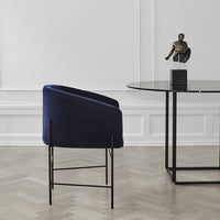 Navy blue velvet chair with sleek black metal legs, set against a minimalist backdrop.