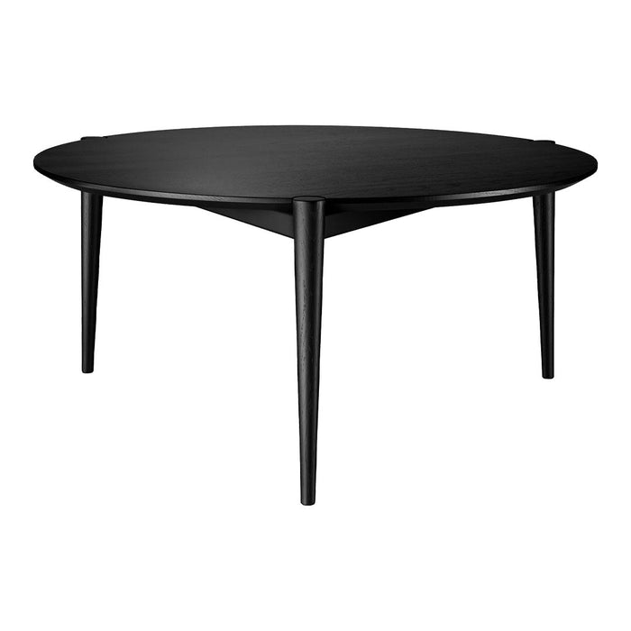 Black round coffee table with sleek, minimalist design and tapered legs, showcasing a smooth, matte finish.