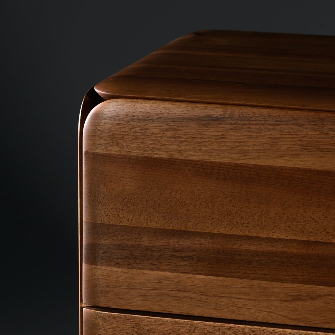Close-up of a smooth walnut wood surface with rich brown hues and subtle horizontal grain patterns.