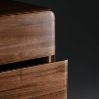 Close-up of a smooth walnut wood surface with a rich, warm brown tone and subtle natural grain patterns.