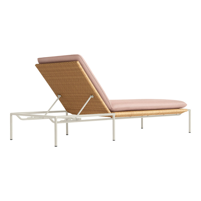 Modern chaise lounge with a soft pink cushion and natural wood accents, set on a sleek white metal frame.