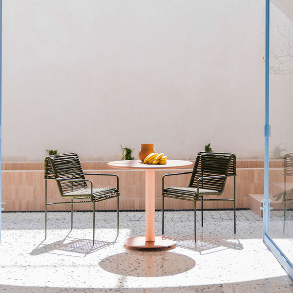 "Green striped chairs and a pink round table set against a minimalist light backdrop, perfect for outdoor spaces."