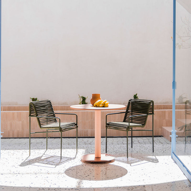 "Green striped chairs and a pink round table set against a minimalist light backdrop, perfect for outdoor spaces."