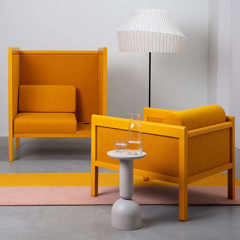 Vibrant yellow armchairs paired with a pastel pink rug and minimalist gray table, accented by a white lamp.