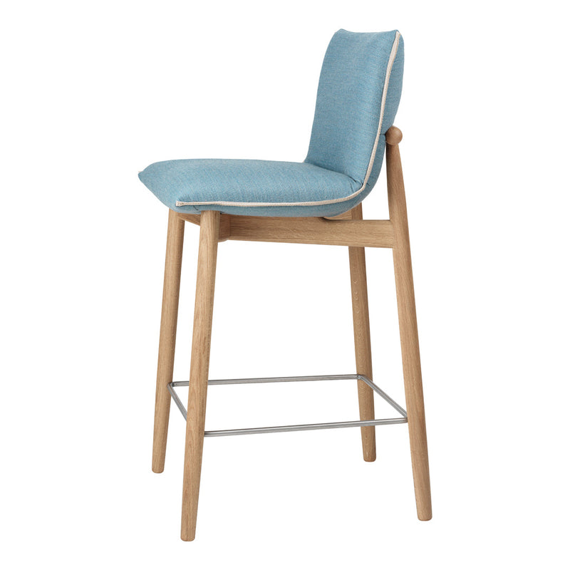 Blue upholstered bar stool with minimalist design and natural wood legs, featuring a light contrast piping.