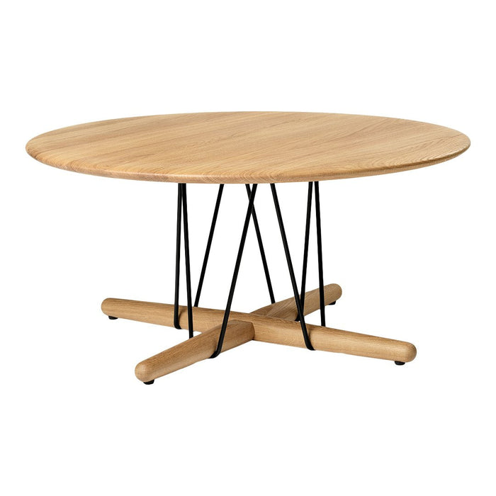 Round wooden table with a light natural finish and black metal legs, featuring a minimalist design.
