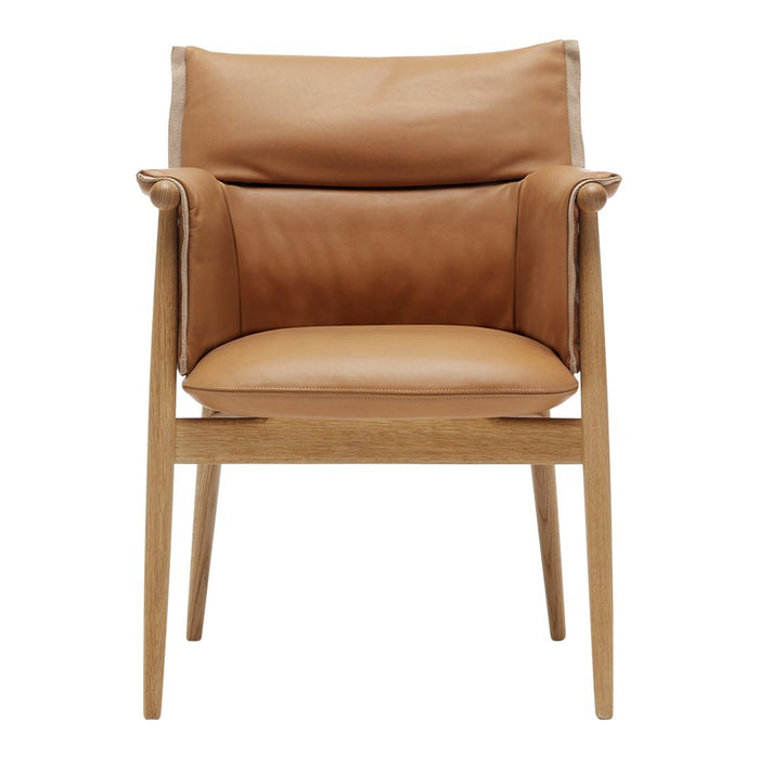 Brown leather armchair with a sleek design and natural wood legs, featuring smooth, minimalist patterns.