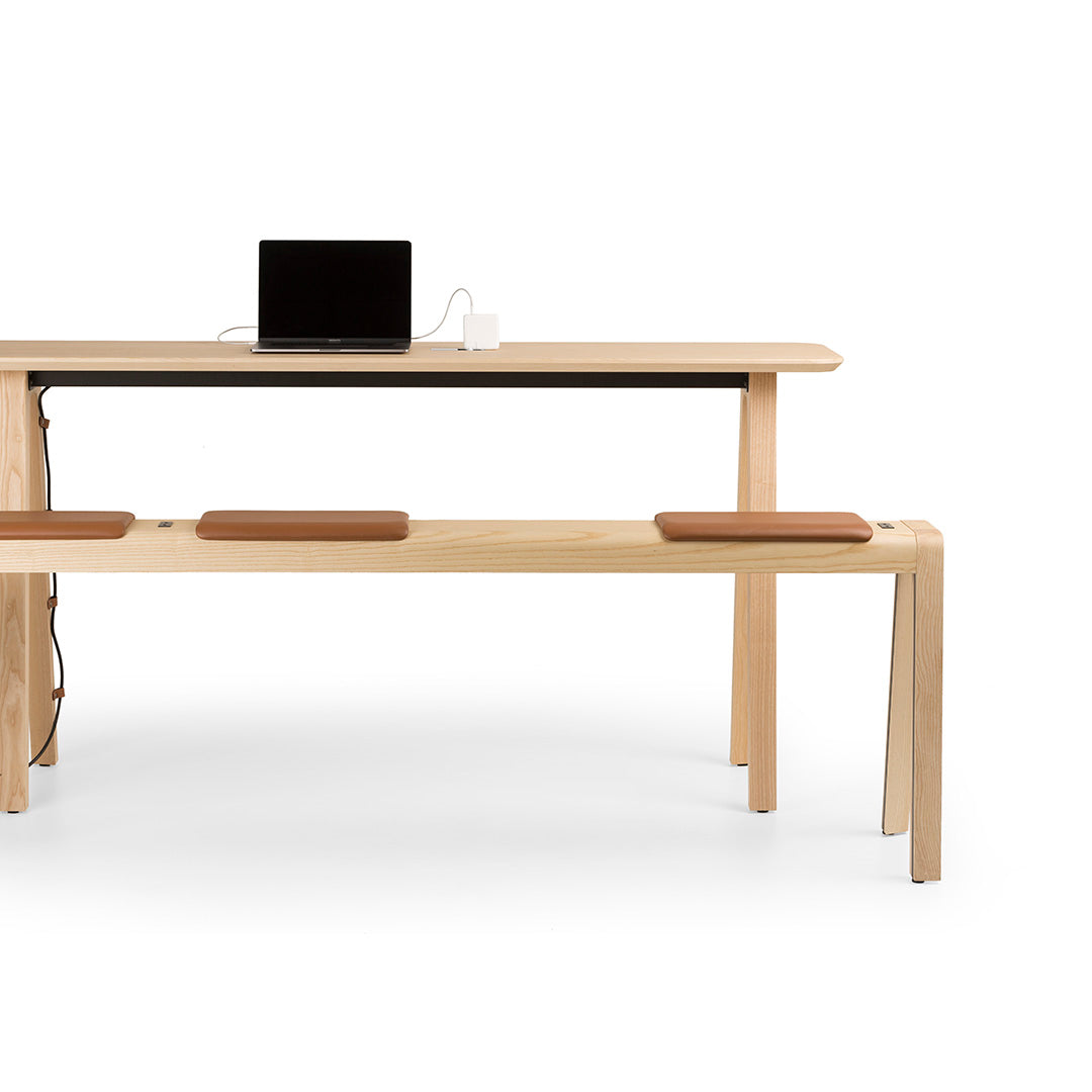 Natural wood desk with a smooth finish, featuring a minimalistic design and light brown leather accents.