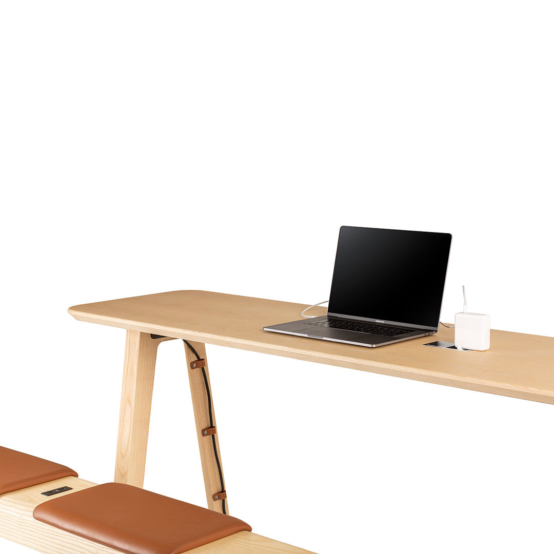 Light wood desk with smooth finish, paired with brown leather cushions, creating a modern, minimalist aesthetic.