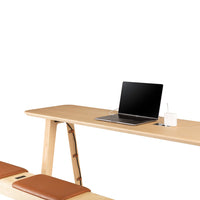 Light wood desk with smooth finish, paired with brown leather cushions, creating a modern, minimalist aesthetic.