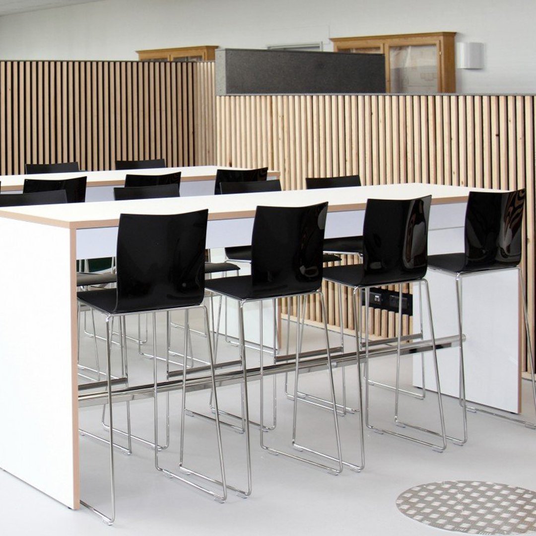Stylish black and white bar stools with sleek chrome legs, set against a minimalist, striped wood backdrop.