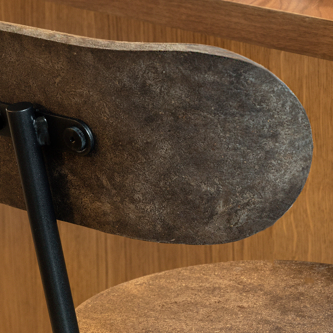 Rustic brown and grey chair with a textured surface and black metal detailing, perfect for industrial decor.