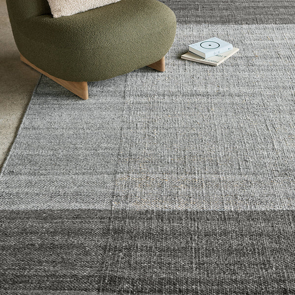 Gray area rug with subtle textured patterns, featuring gradients from light to dark tones. Stylish and modern design.