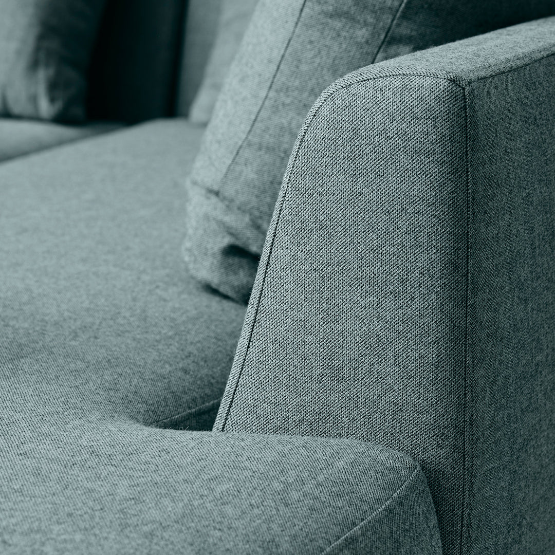 Textured gray fabric sofa with soft angles and coordinating throw pillows in a modern design.