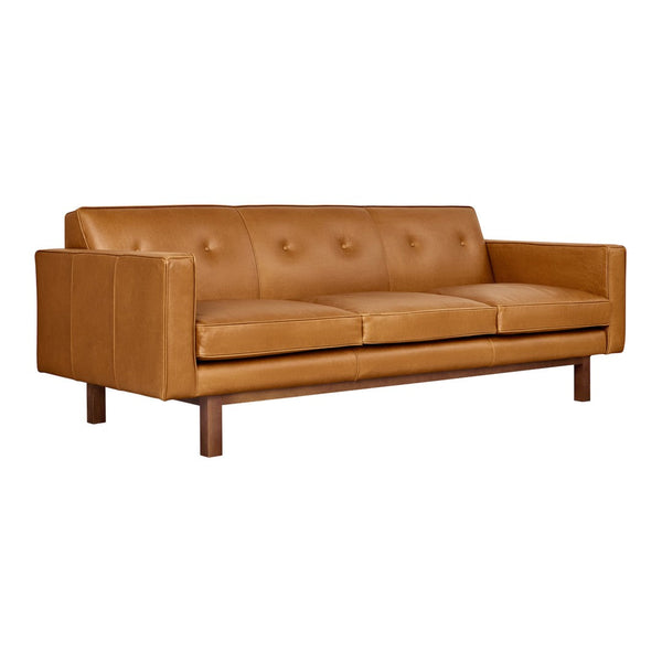 Mid-century modern sofa in rich caramel leather with button tufting and sleek wooden legs. Ideal for stylish interiors.