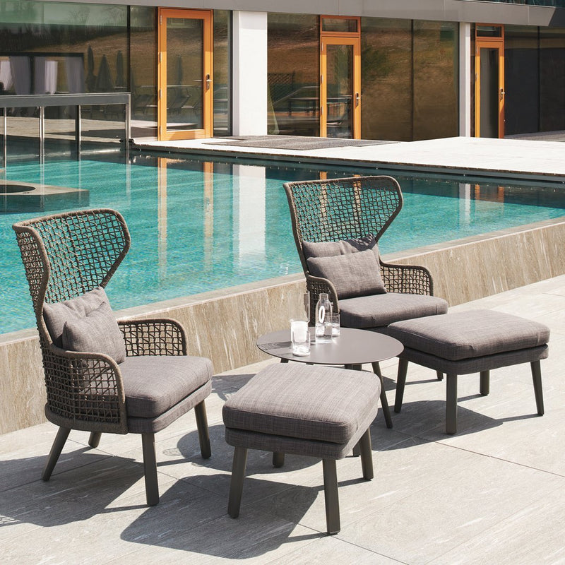 Modern outdoor furniture set featuring gray cushions, brown woven patterns, and a sleek black side table by a pool.