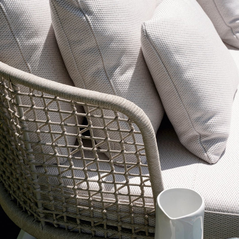 Neutral-toned outdoor sofa with textured fabric cushions and woven backrest pattern. Elegant and modern design.