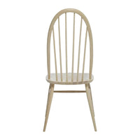 Light natural wood chair with a smooth finish and vertical slat pattern, featuring an arched back and tapered legs.