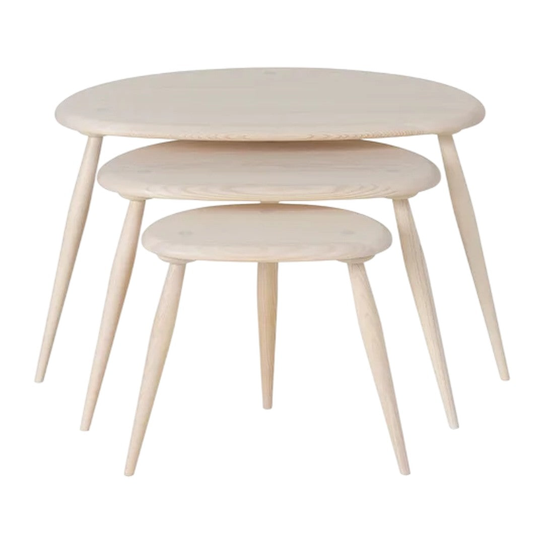 Set of three light wood nesting tables with smooth, round tops and tapered legs. Clean, minimalist design.