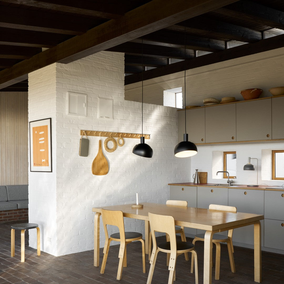 Modern kitchen with wooden dining table and chairs, white walls, and pendant lights.