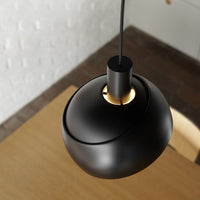Black pendant light on a wooden surface with a white textured wall background