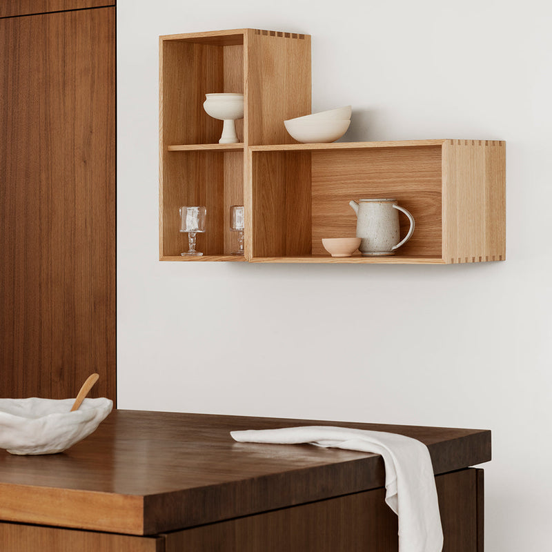 "Light wood wall shelf with natural grain, displaying white and beige dishware against a neutral wall backdrop."
