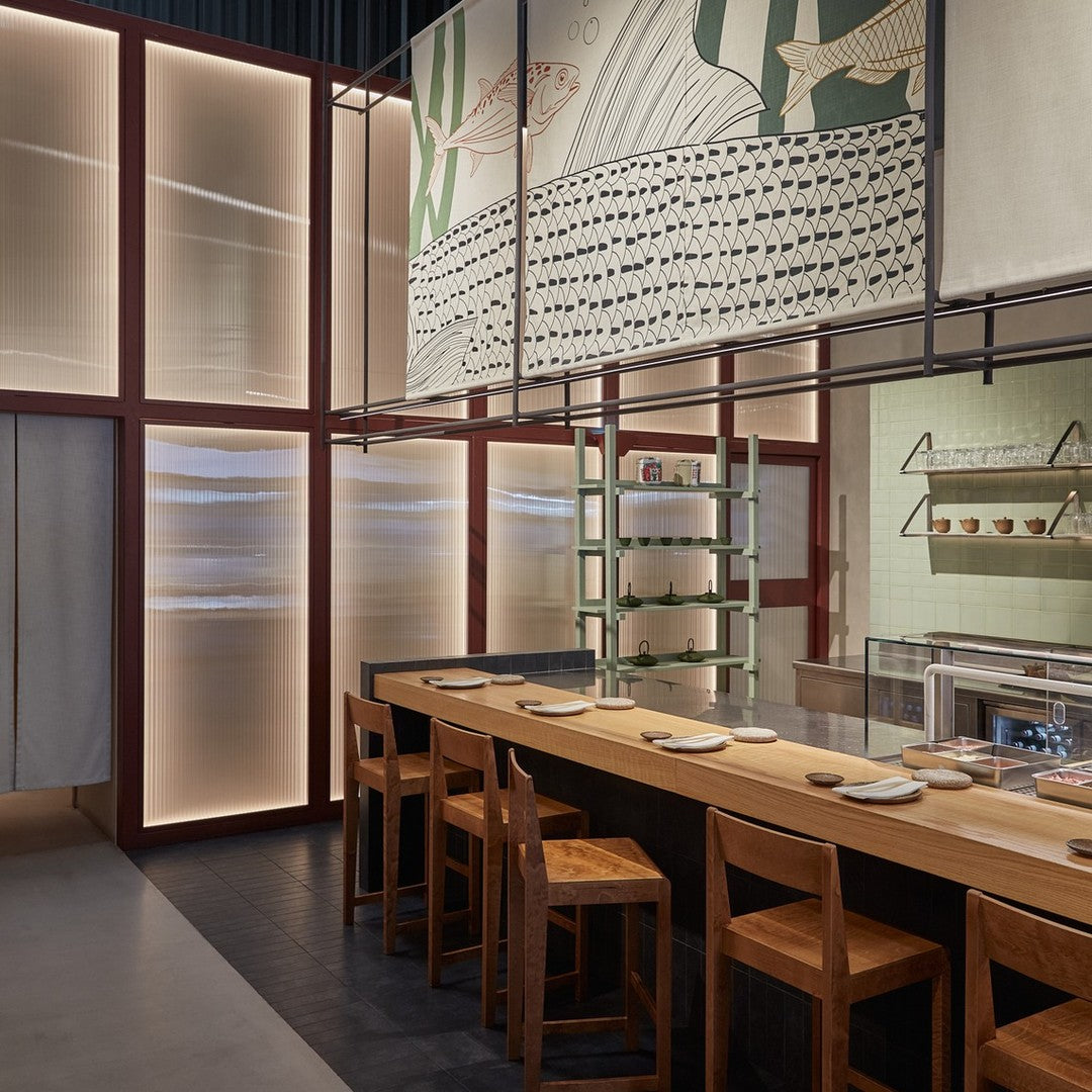 Modern restaurant interior featuring neutral tones, soft blues, and intricate wall patterns. Sleek wood furniture accents.
