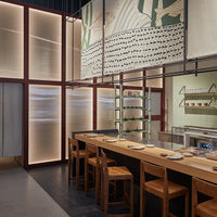 Modern restaurant interior featuring neutral tones, soft blues, and intricate wall patterns. Sleek wood furniture accents.