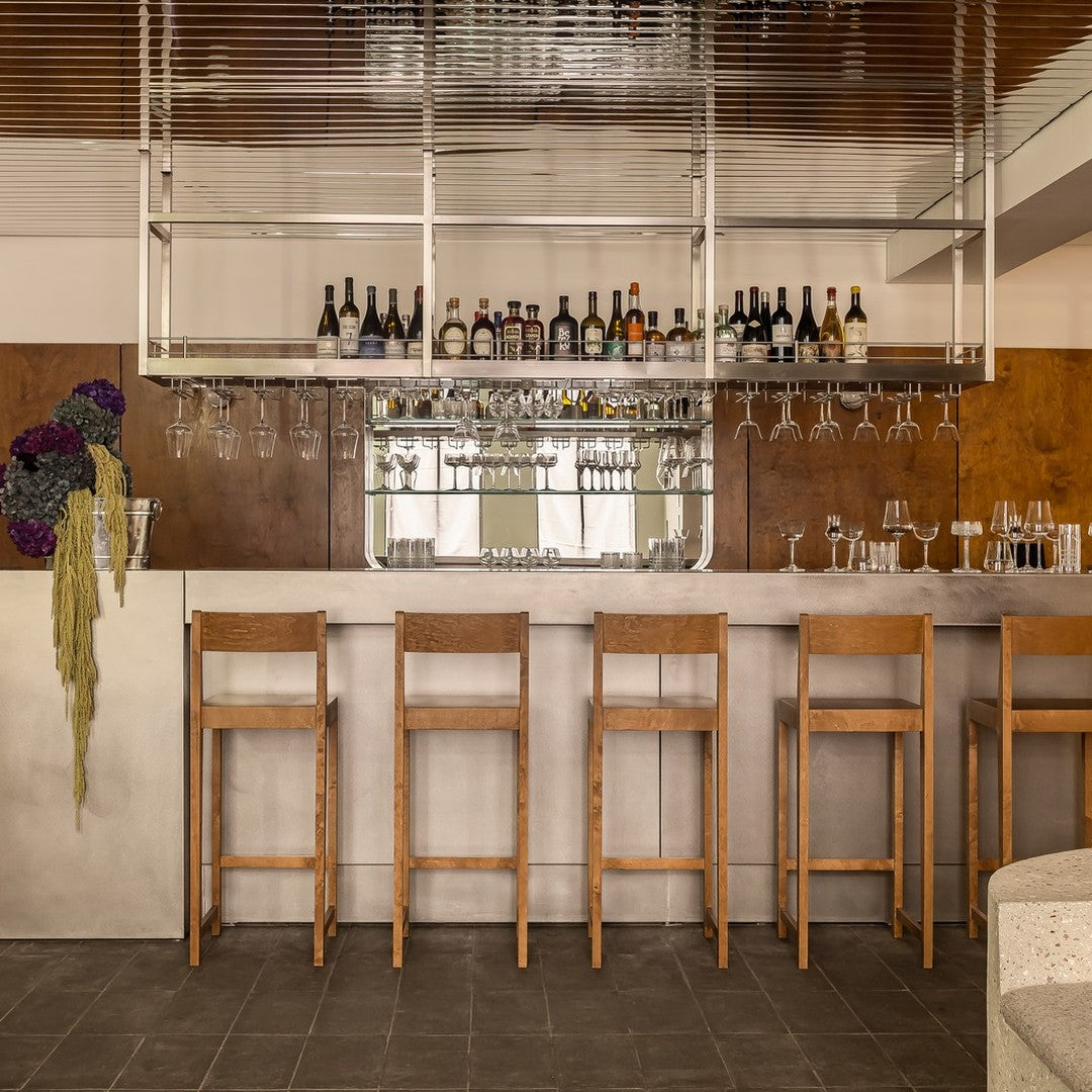 Modern bar with wooden stools, featuring earthy tones, polished surfaces, and a sleek, minimalist design.