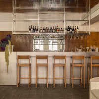 Modern bar with wooden stools, featuring earthy tones, polished surfaces, and a sleek, minimalist design.