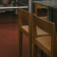Wooden chairs with a natural finish against a warm red floor, featuring a minimalist design.
