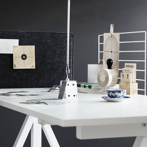 Modern white desk with a black backdrop, featuring geometric patterns and earthy tones in desk accessories.