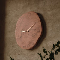 "Unique copper wall clock with natural wood patterns and a minimalist design, featuring gold-toned clock hands."