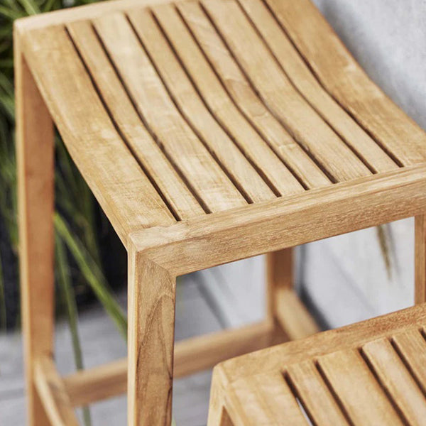 "Close-up of a natural wood stool with vertical slats and a light brown finish."