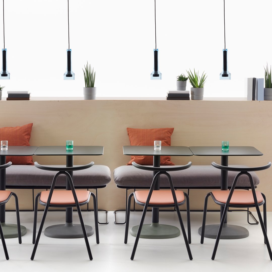 "Modern cafe scene featuring black chairs, peach cushions, gray tables, and green accents with minimalist lighting."