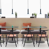 "Modern cafe scene featuring black chairs, peach cushions, gray tables, and green accents with minimalist lighting."