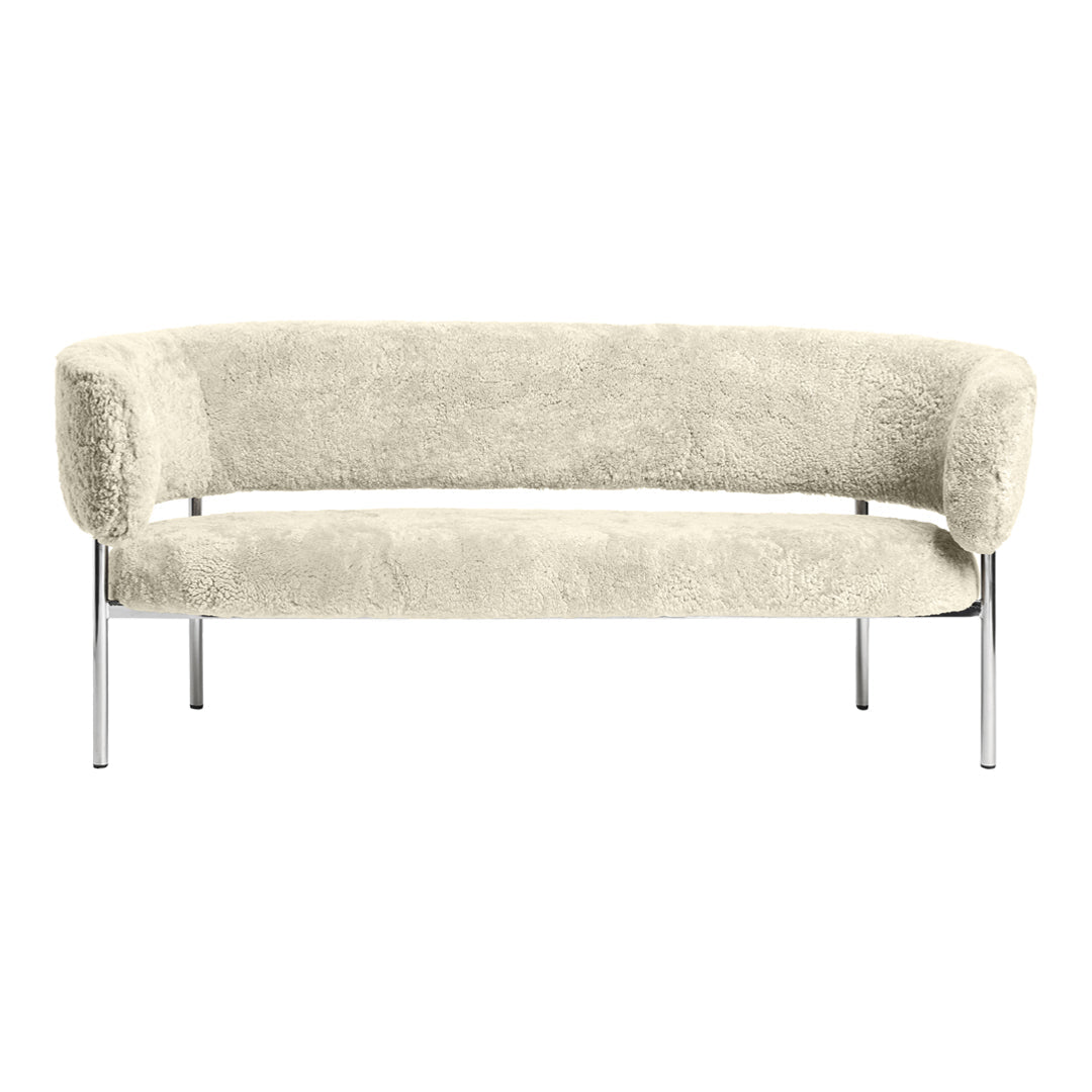 Cream-colored curved sofa with a soft, textured finish and sleek chrome legs. Elegant and modern design.