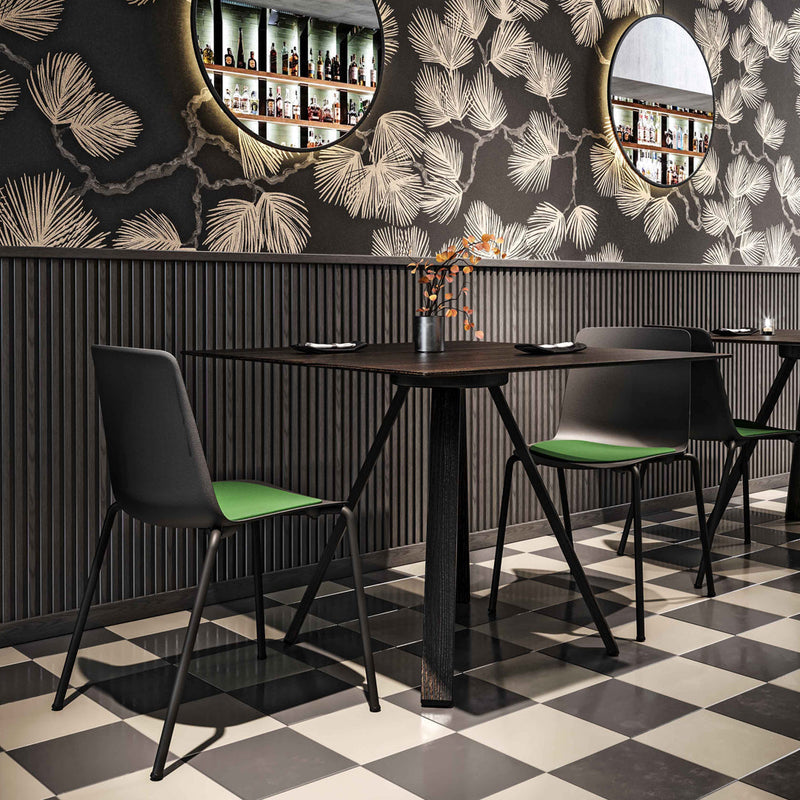 Modern black and green chairs set against a floral patterned black wallpaper and checkered floor.