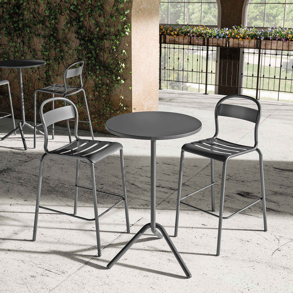 Modern black metal table and chairs with sleek design, set against a stone floor and greenery backdrop.